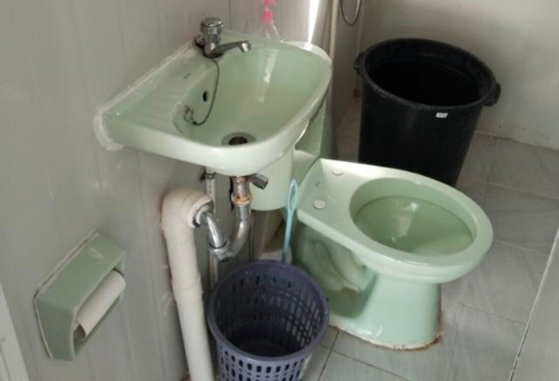 Un baño con lavamanos, inodoro y cubo de basura.