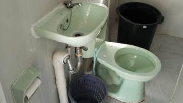 Un baño con lavamanos, inodoro y cubo de basura.