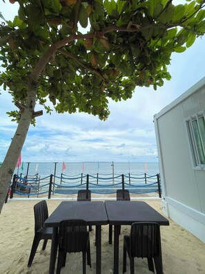 A beachside seating area with a table and chairs, a rope barrier, and a view of the sea.
