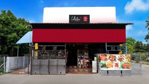 Un edificio con facciata rossa e bianca, un cartello sopra l'ingresso e un espositore di cibo all'esterno.