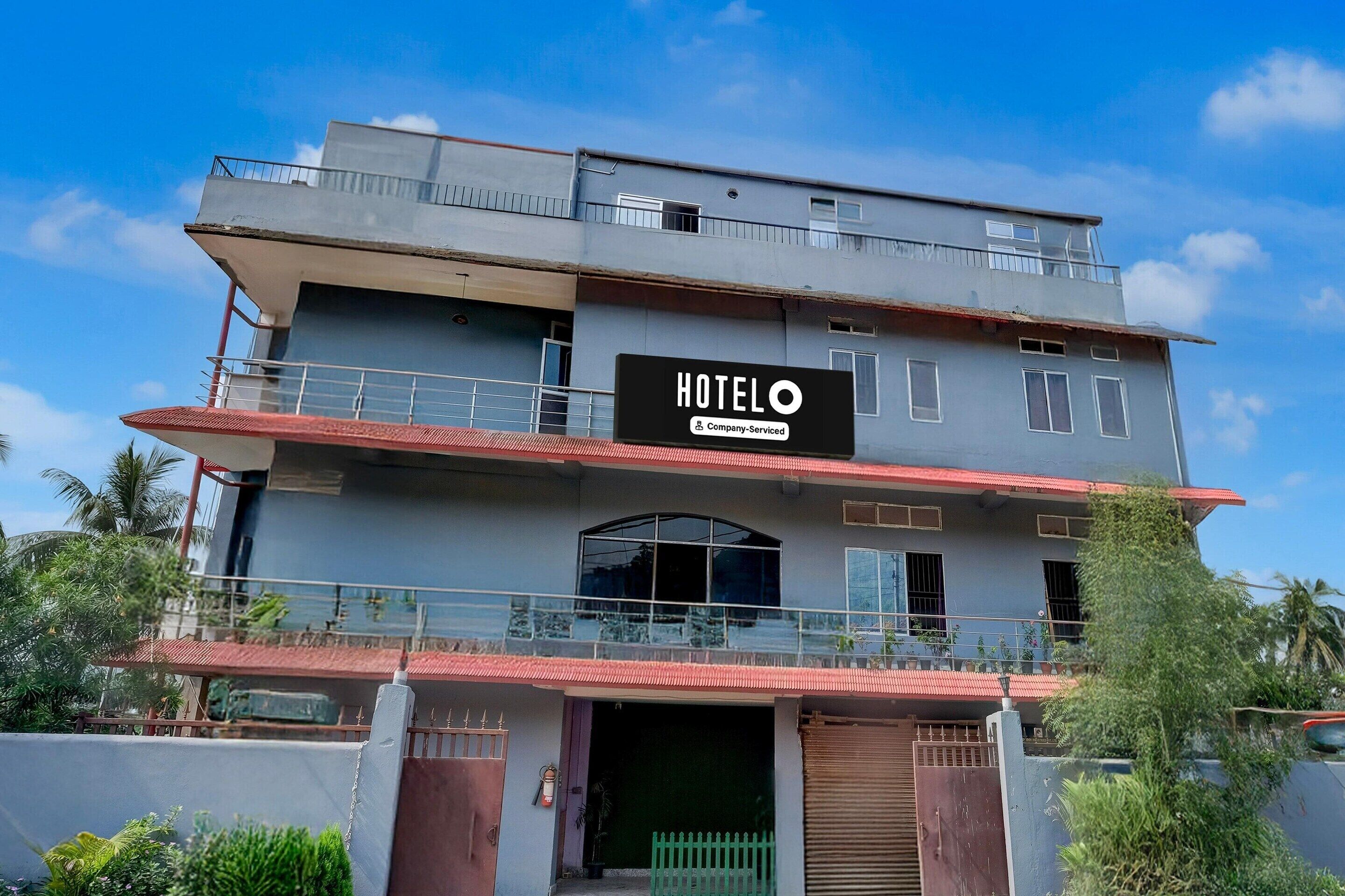 Ett hotell med flera våningar, ett stort och väl synligt skylt med texten ”HOTEL O”, balkonger och en grind vid ingången.