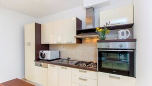 Een moderne keuken met een magnetron, fornuis, oven en een vaas met bloemen op het aanrecht.
