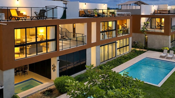 Une maison moderne à plusieurs étages, dotée d’une piscine, d’un espace extérieur aménagé et d’un intérieur bien éclairé.