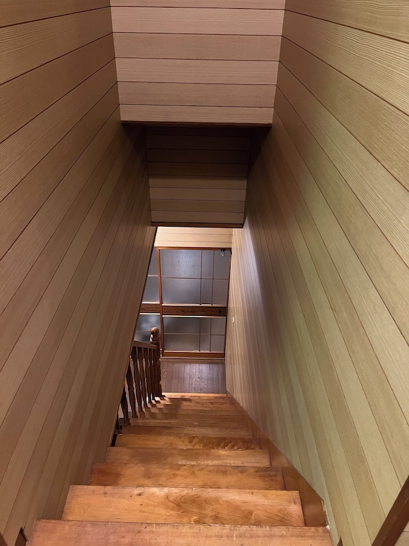 Un escalier en bois offrant une vue sur une piĂšce situĂ©e Ă lâĂ©tage supĂ©rieur.