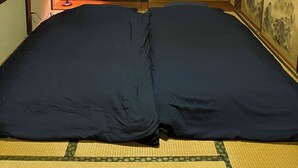 Um quarto japonês tradicional com tatames, futon, divisória shoji e um lampião de papel suspenso.
