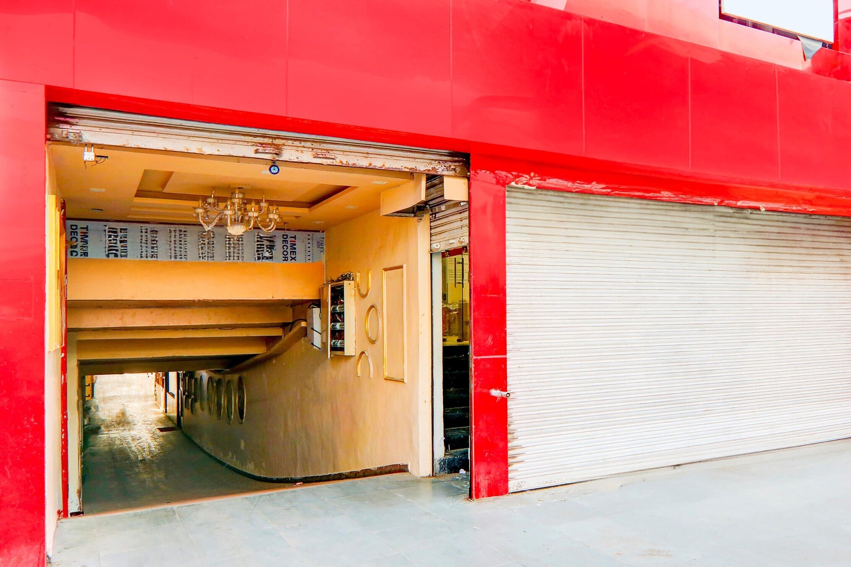 A red building with a closed garage door, a visible interior hallway, and a chandelier.