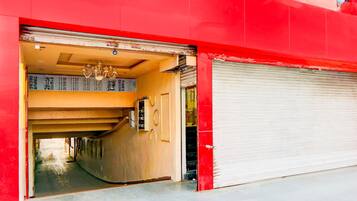 A red building with a closed garage door, a visible interior hallway, and a chandelier.