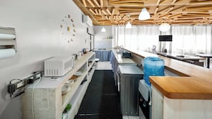 Una cocina con vigas de madera en el techo, microondas, dispensador de agua y un lavamanos.