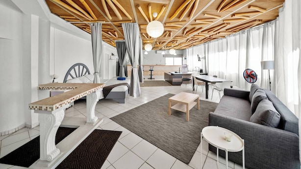 Un interior moderno con techo de madera, un sofá, una mesa de comedor y una silla.