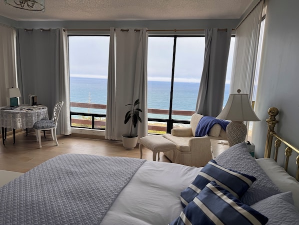 Ein Hotelzimmer mit einem großen Bett, einer Sitzecke mit Tisch und Meerblick.