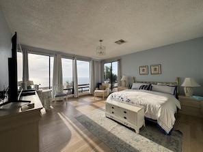 Ein geräumiges Schlafzimmer mit einem großen Bett, einem Schreibtisch und Meerblick.