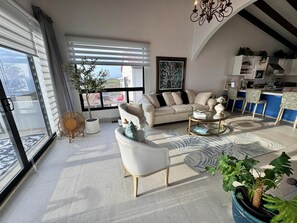 Ein modernes Wohnzimmer mit einer Couch, einem Couchtisch und Blick ins Freie.