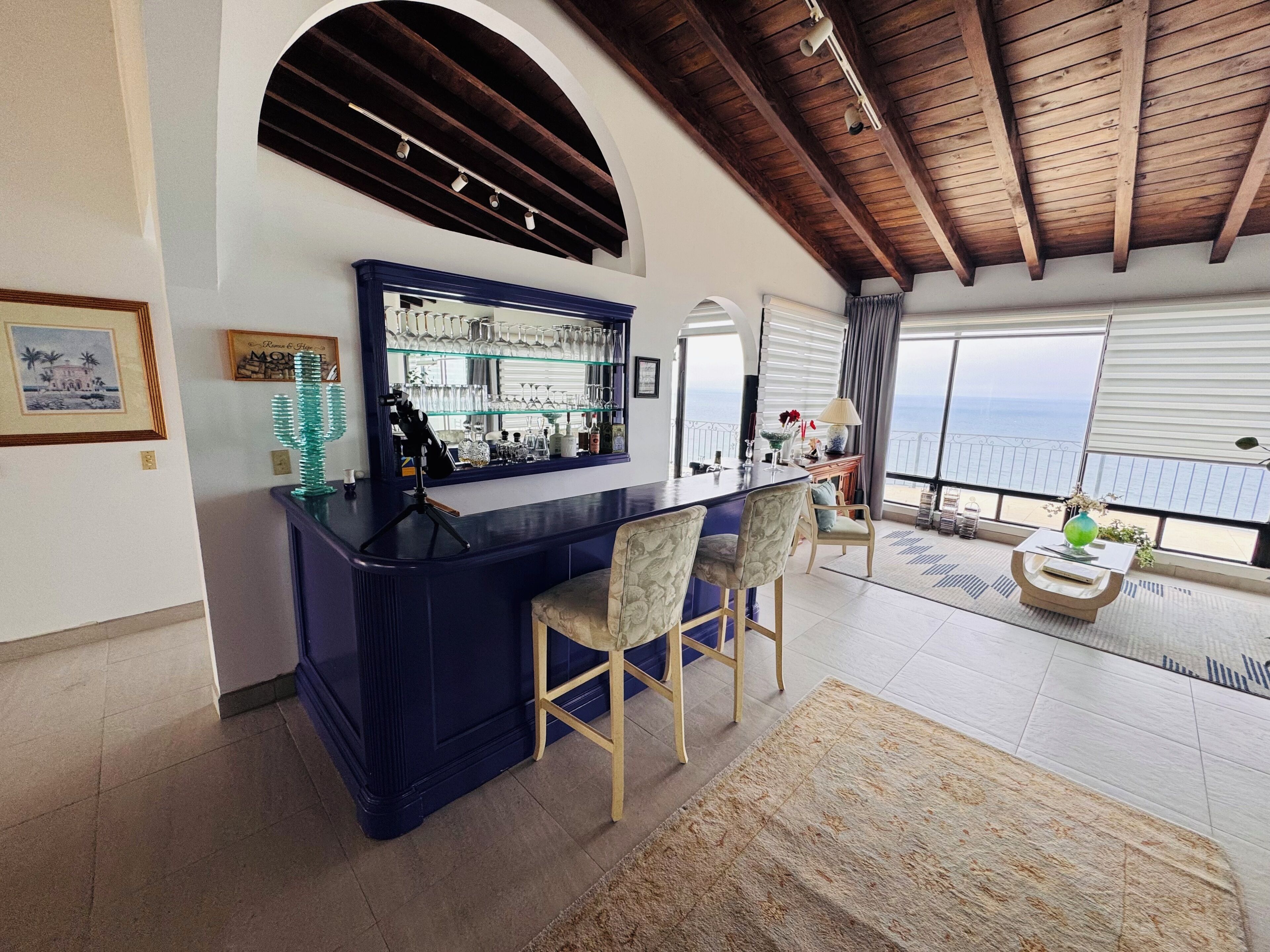 Un espace bar avec un comptoir, des chaises et une vue sur la mer.