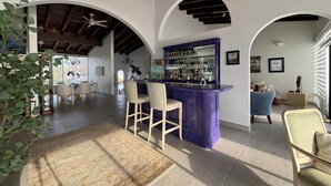 A spacious living area with a bar, seating, and a view through an archway. - VILLA ESPERANZA — OCEANFRONT LIVING WHERE THE FAIRWAY MEETS THE SEA (Ensenada)