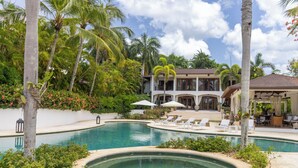 A pool area with lounge chairs, a gazebo, and a large house with multiple windows and a covered patio. - Casa Delmar: Private Beachfront Estate with Chef, 2 Butlers ,Staff & Ocean Views (La Romana)