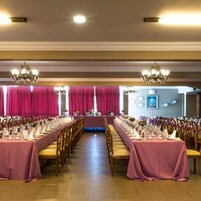 Un salón de banquetes con mesas largas, candelabros y vistas al exterior.