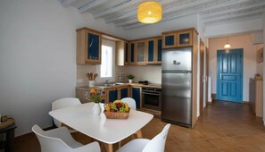 Eine moderne Küche mit Holzausbau, einem Edelstahl-Kühlschrank und einer Essecke mit weißen Stühlen und einem Tisch.