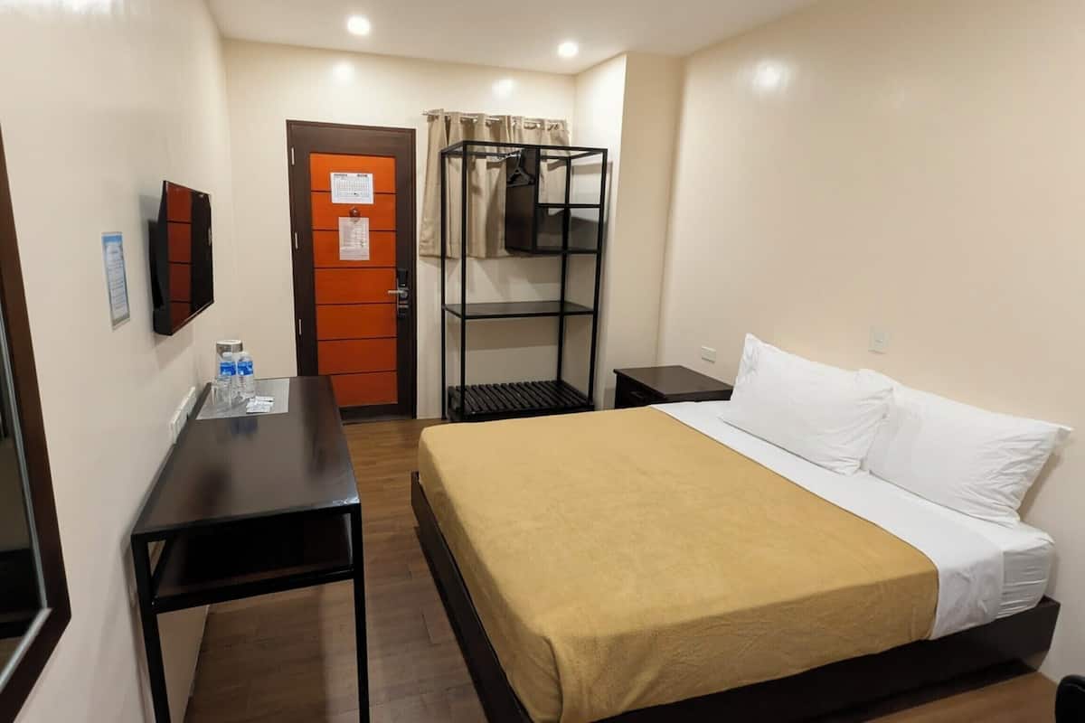 A hotel room with a bed, a desk, a TV, a wardrobe, and a bunk bed.