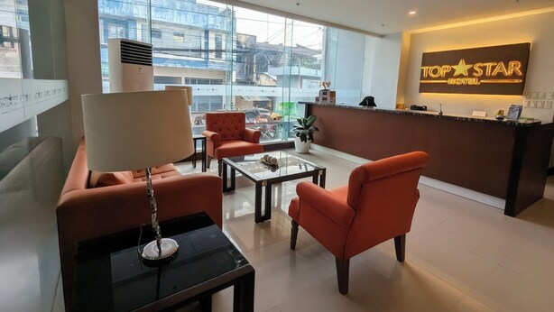 A modern hotel lobby with a reception desk, seating area, and large windows offering city views.