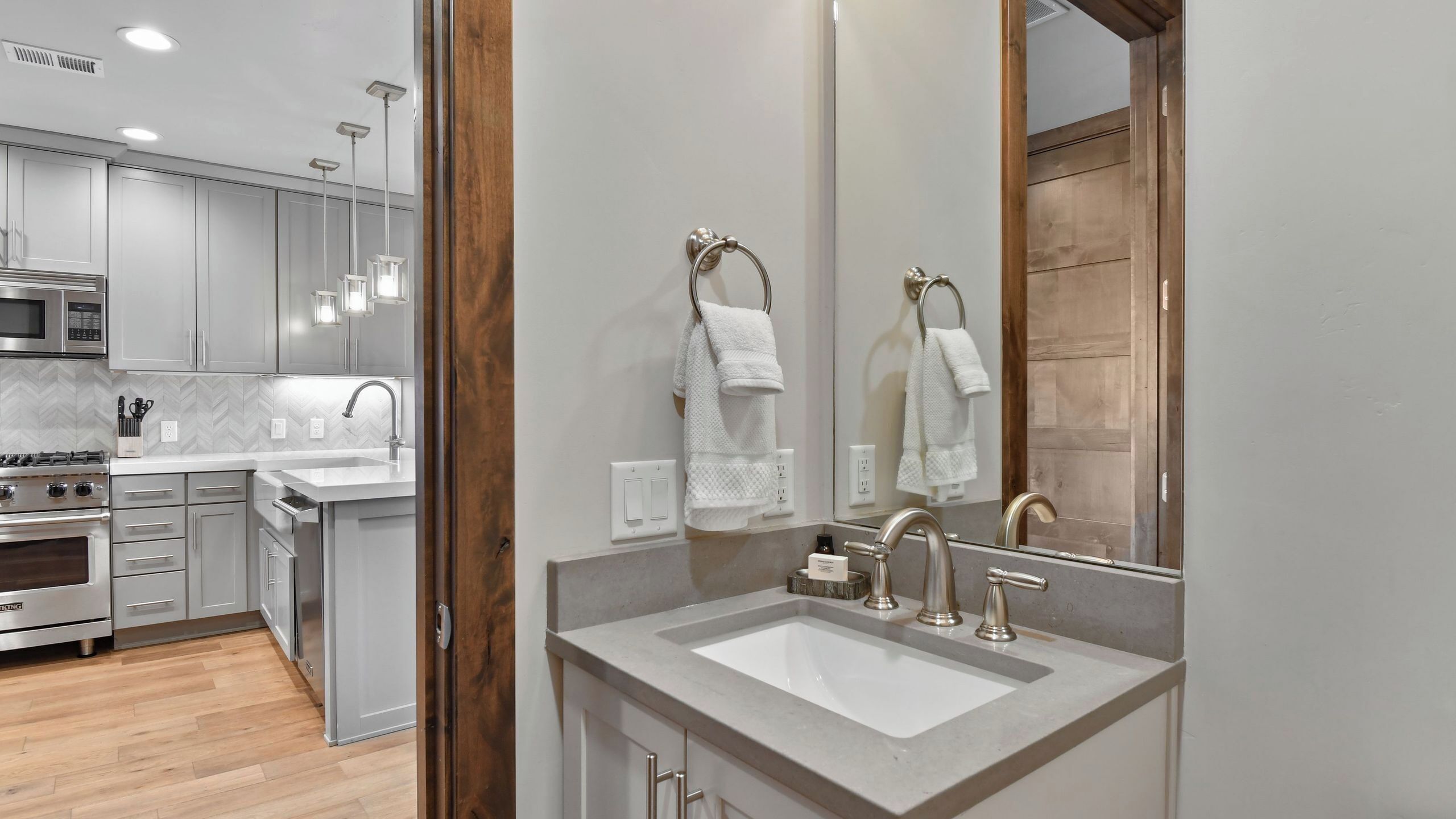 A modern kitchen with stainless steel appliances, a white countertop, and a wooden door frame.