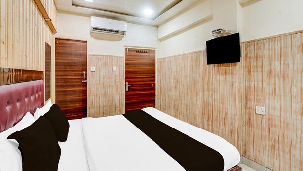 A bedroom with a bed, wooden wardrobe, an air conditioning unit, and a television. - Collection O Tajganj West Gate (Agra)