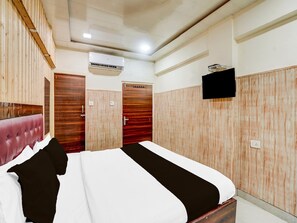 A bedroom with a bed, wooden wardrobe, an air conditioning unit, and a television. - Collection O Tajganj West Gate (Agra)