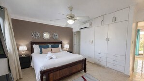 Una camera da letto con un letto, lampade da comodino, una ventola a soffitto, un armadio e pannelli decorativi a parete.