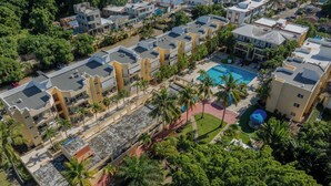 Vista aerea di una zona residenziale con edifici moderni, una piscina e palme.