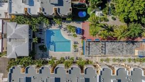 Vista aerea di un hotel con piscina, palme e terrazza sul tetto.