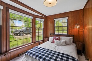 Ein Schlafzimmer mit einem großen Bett, Holzvertäfelung und mehreren Fenstern.