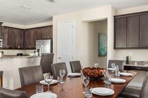 Un espace repas avec une longue table dressée pour six personnes, entourée de chaises en bois foncé.