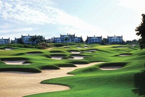 A golf course with bunkers and a row of houses in the background. - 6BR Reunion Escape w/ Pool, Spa & Outdoor Patio (Kissimmee)