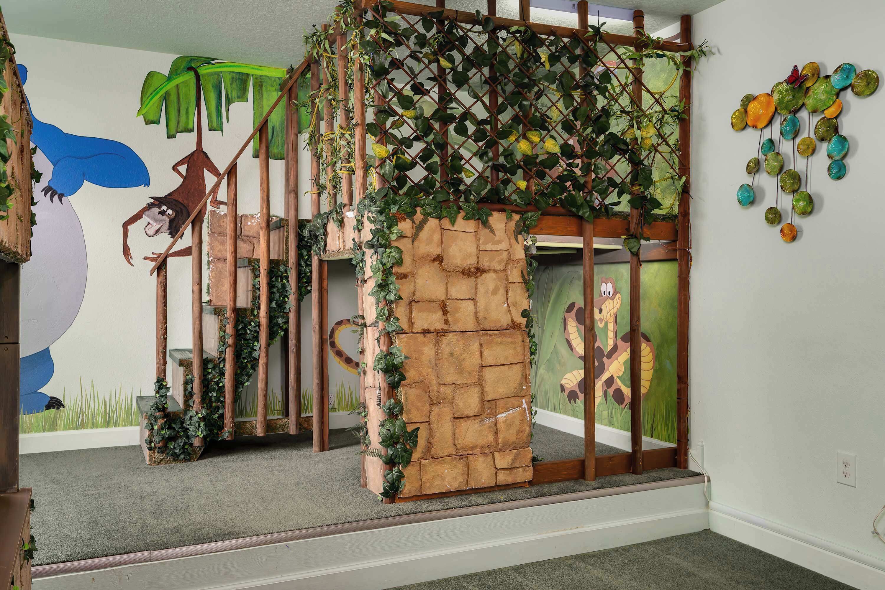 A play area with a climbing structure, a mural, and a hanging decoration.