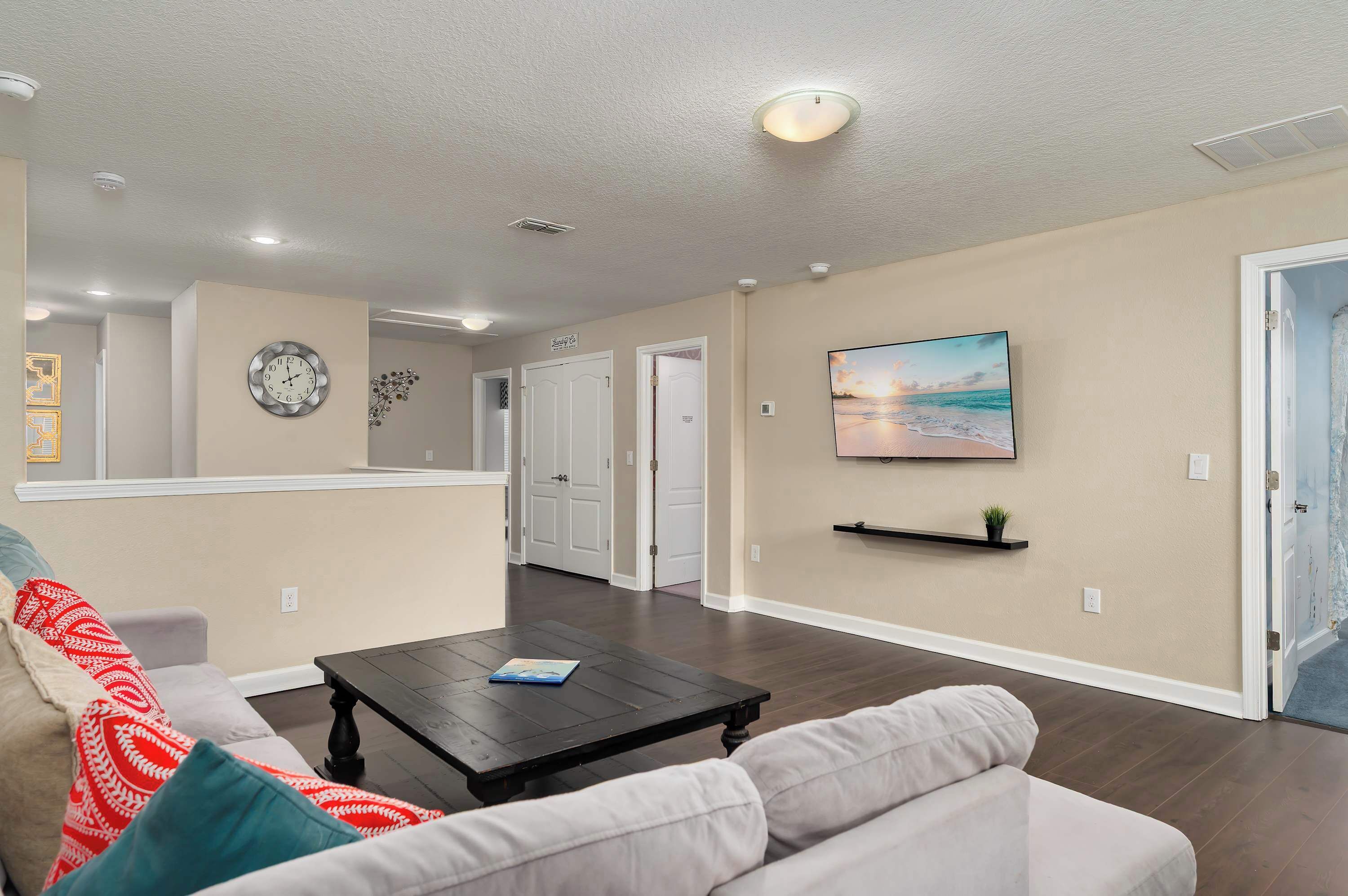 A living room with a sofa, coffee table, and TV. There are doors leading to other rooms.