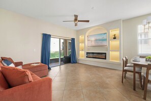 A living room with a sofa, a dining table with chairs, a fireplace, and a ceiling fan. - Bright townhouse w/ lazy river & resort pool (Davenport)