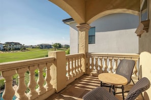 Un balcon donnant sur un terrain de golf, une table avec des chaises et une fenêtre.