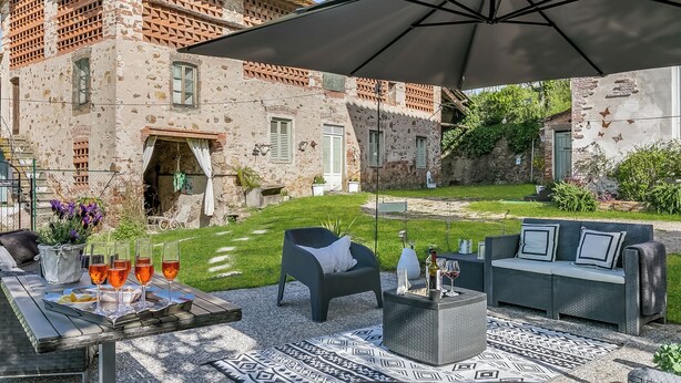 An outdoor patio with a table set for four, a sofa, and an umbrella. - Paradise Family Apartment | Hot Tub&Garden, Lucca, Italy (Lucca)