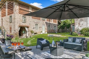 Eine Terrasse im Freien mit Tisch für vier Personen, einer Couch und einem Sonnenschirm.