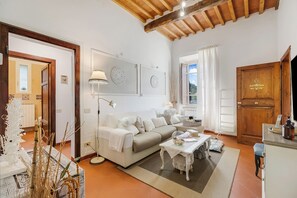 A living room with a sofa, a coffee table, a lamp, and a wooden cabinet. - Romantic Apartment near Lucca, Lucca, Italy (Lucca)