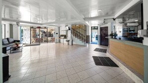 A spacious lobby with a sofa, coffee table, and a reception desk. - Cheap Hotel Room in Sosua Center! (Sosúa)