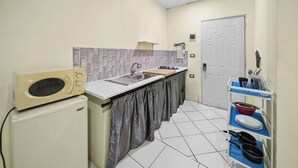 A compact kitchen with a microwave, sink, and a small cabinet. - Cheap Hotel Room in Sosua Center! (Sosúa)