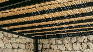 A stone-walled room with a hanging chair, a table, and a bathtub. - Gumus Yazar Hotel (Kaş)