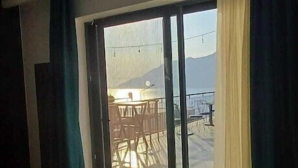 A room with a bed, a large window, and a view of an outdoor area with a table and chairs. - Gumus Yazar Hotel (Kaş)