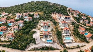A coastal residential area with houses, some with pools, surrounded by greenery and the sea. - Gumus Yazar Hotel (Kaş)