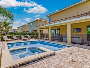 A swimming pool with lounge chairs, a covered seating area, and a flat roofed building. - Outdoor TV, Air Hockey, Foosball, Epic Game Room, Basketball Arcade, 1GB: Summer Breeze (Kissimmee)
