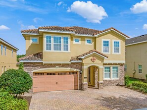 A two-story house with a garage, a well-maintained lawn, and a clear sky. - Outdoor TV, Air Hockey, Foosball, Epic Game Room, Basketball Arcade, 1GB: Summer Breeze (Kissimmee)