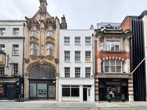 Eine Reihe von Gebäuden mit unterschiedlichen Architekturstilen, darunter eine weiße Fassade, ein Gebäude aus roten Ziegeln und ein Bauwerk mit aufwendiger Gestaltung.
