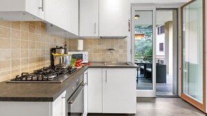 Eine moderne Küche mit weißen Schränken, einem Gasherd und Blick auf die Terrasse.