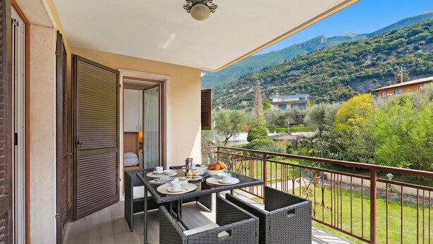 Ein Balkon mit Esstisch, Blick auf die Landschaft und ein Berg im Hintergrund.