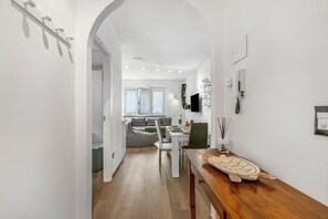 A modern interior with a dining area, a sofa, and a wooden table with a decorative object. - Margherita Apartment - Lake and Mountain Views, Malcesine, Italy (Malcesine)